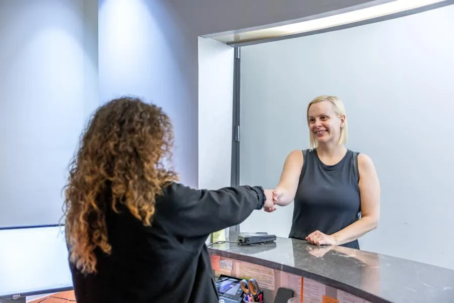 A Wall Street Orthodontics team member greeting a smiling patient at the front desk