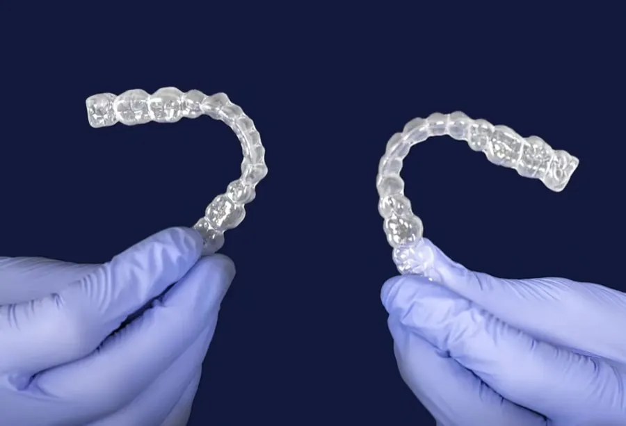 Two clear aligner trays held side by side, one for each arch