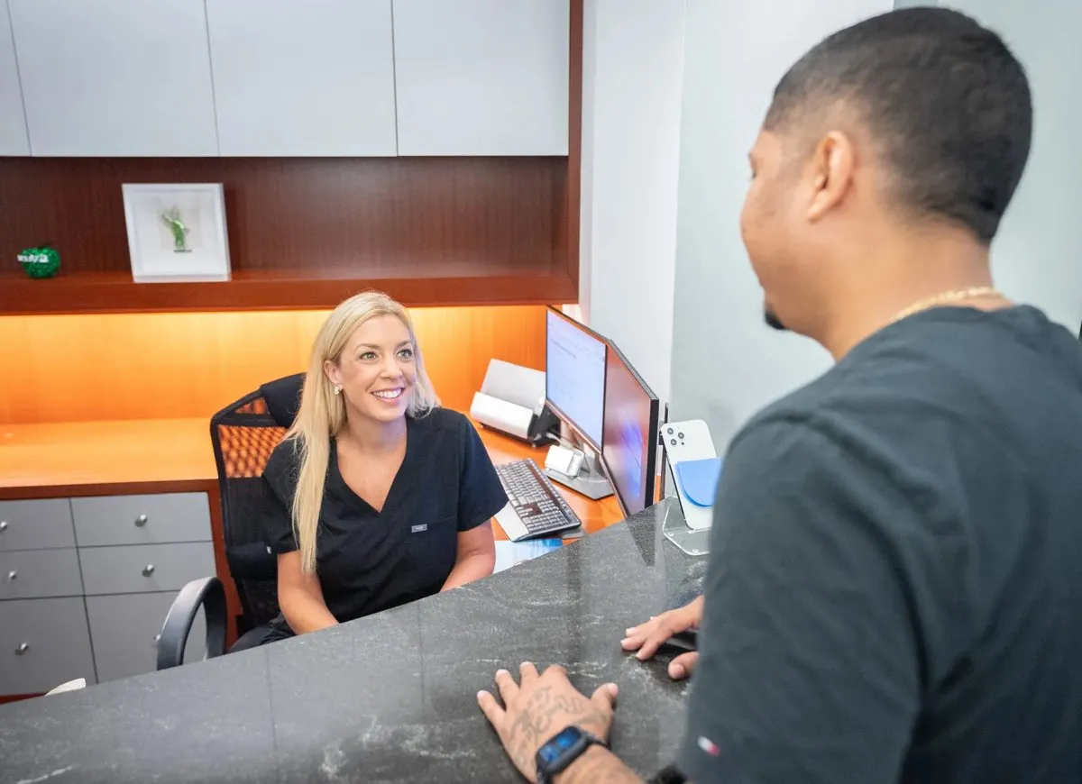 A Wall Street Orthodontics team member at the front desk talking with a patient